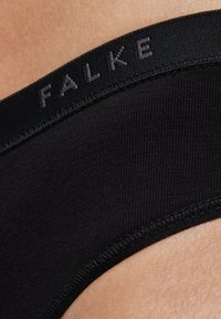 Zwarte stoffen slip met een gladde textuur, zachte elastische tailleband met het "FALKE"-logo en gevormde randen voor pasvorm en comfort.