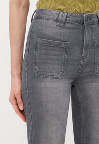 Hallhalli denim püksid sobiva disainiga, kõrge vöökoht ja kaks tagataskut. Kangas on õrnalt tekstureeritud välimusega.