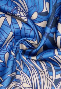 Tessuto blu e beige con un motivo vorticoso; presenta una texture liscia, linee blu ben definite e forme astratte su uno sfondo chiaro.
