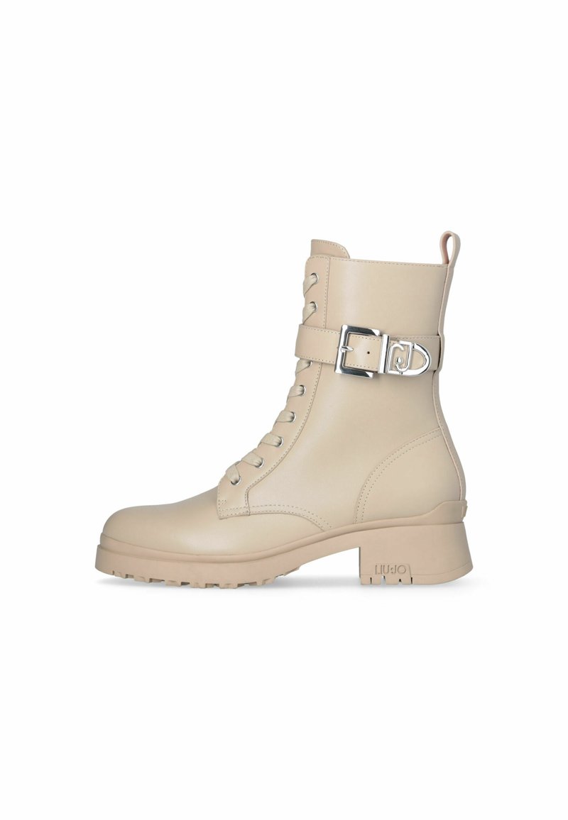 Stivaletti beige in pelle, con punta tonda, lacci anteriori, una fibbia laterale e un tacco basso a blocco, dotati di suola texturizzata per una buona aderenza.