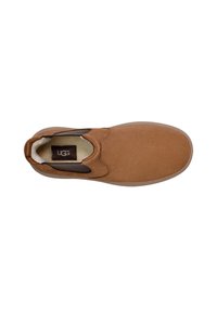 Zapato marrón de ante sin cordones con paneles elásticos a los lados, suela de goma y forro interior acolchado. Logotipo de UGG visible en la plantilla.