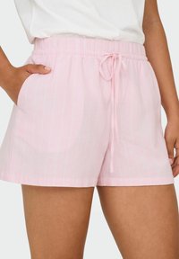 Shorts à cordon de serrage rose clair avec des rayures verticales blanches, taille élastique et poches latérales. Tissu doux avec une coupe décontractée.
