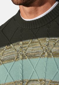 Dunkelgrüner Strickpullover mit strukturierten diagonalen Mustern und horizontalen Streifen in Hellblau und erdigen Tönen. Gerippte Kragenverzierung.