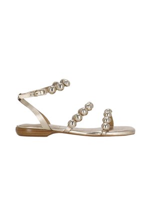 Sandalo piatto metallico oro con cinturino alla caviglia e tre cinturini decorati con perle sul piede e sulle dita, suola in legno visibile.