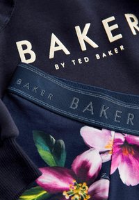 Felpa blu navy con ricamo crema "BAKER by TED BAKER" e vita floreale con stampe floreali rosa e verdi e accenti blu.