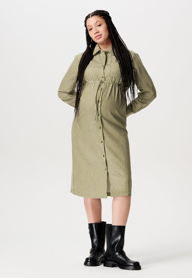 Gestreiftes grünes Hemdblusenkleid mit tailliertem Schnitt, langen Ärmeln, Knopfverschluss und einer Vordertasche, kombiniert mit schwarzen knielangen Stiefeln.