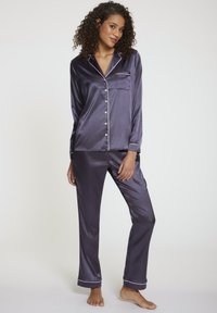 Navy Satin-Pyjamas mit weißen Paspeln, bestehend aus einem knöpfbaren Oberteil, langen Ärmeln und passenden, knöchellangen Hosen mit einer Taschenapplikation.