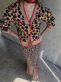 Beżowy kardigan w panterkę z czerwonymi akcentami, w zestawie ze spódnicą w panterkę. Posiada duże guziki i aplikacje w kształcie wiśni.