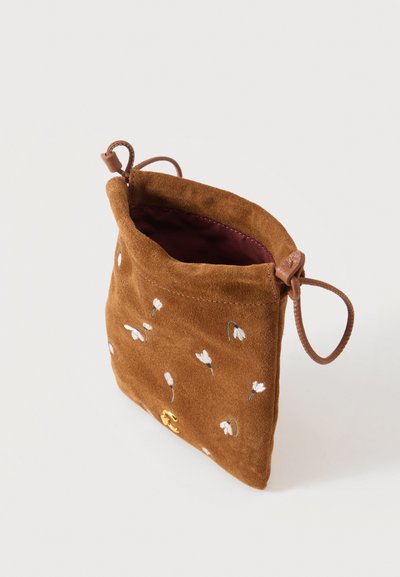 Petite pochette en daim marron avec broderie de fleurs blanches, intérieur grenat, cordon en cuir ajustable et petit détail de fermoir doré.