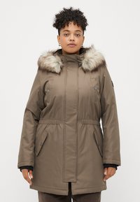 Parka castanho isolado com capuz de pele sintética, cintura elástica e bolsos laterais. Tecido liso com uma textura ligeiramente brilhante.