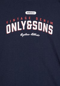 Marineblå bomulls-t-skjorte med fed hvit og rød tekst som leser "VINTAGE DENIM ONLY&SONS" med "MMXIII" øverst.