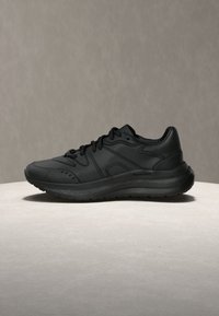 Μαύρο αθλητικό παπούτσι με λείο δερμάτινο επάνω μέρος, υφασμένο μεσαίο πέλμα και μαξιλαρωμένη σόλα. Διαθέτει περίτεχνη ραφή και στρογγυλεμένο σχέδιο μύτης.