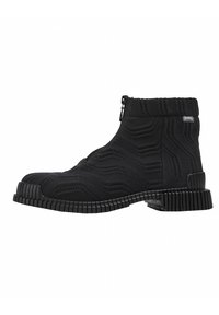 Bottines noires à cheville avec une tige en maille texturée, dotées d'une fermeture éclair et d'une semelle en caoutchouc rainurée pour une meilleure adhérence. Motif géométrique unique sur le tissu.
