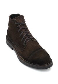 Brown suede ankle boot featuring a cap toe, round laces, and a thick rubber sole, with stitching detail around the shoe's edge.