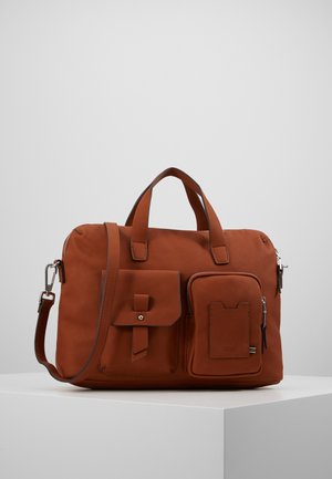 Sac à main en cuir marron avec deux poches avant, poignées supérieures et une bandoulière amovible, exposé sur un socle blanc.