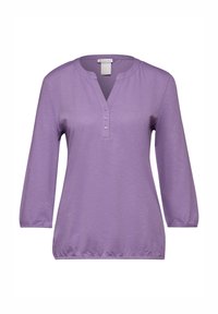 Maglia viola a maniche lunghe con scollo a V, abbottonatura con tre bottoni e maniche arricciate. Realizzata in un tessuto morbido e leggero con una sottile texture.