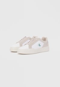 Witte sneakers met lichtbeige suède accenten, ronde neus, platte veters, logo in het groen en een getextureerde rubberen zool.