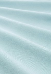 Jasnoniebieska bawełniana tkanina o gładkiej fakturze, z delikatnymi żeberkami i łagodnymi fałdami, tworzącymi miękki, płynny wygląd.