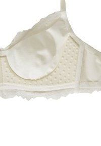 Soutien-gorge di colore crema chiaro con tessuto morbido, pannello a pois texturizzati e bordino in pizzo lungo la parte inferiore. Presenta spalline regolabili.