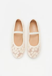 Ballet flats con una parte superiore in rete beige chiaro, caratterizzati da un motivo floreale, una fascia elastica e una foderatura interna marrone. Texture complessivamente liscia.