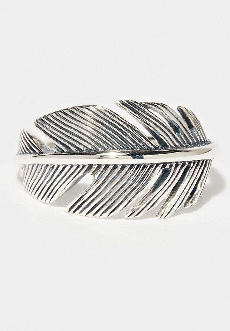 Bague en argent en forme de plume détaillée avec des rainures texturées et des sections ajourées, présentée sur un fond blanc.