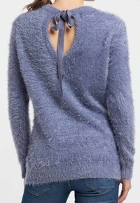 Luddig blå tröja med rundad baköppning som hålls på plats med ett snörning, med långa ärmar och en mjuk textur.