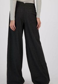 Brede broek in donkergrijze stof met subtiele streepjes. Kenmerkende tailleband met achterzakken en een gladde textuur.