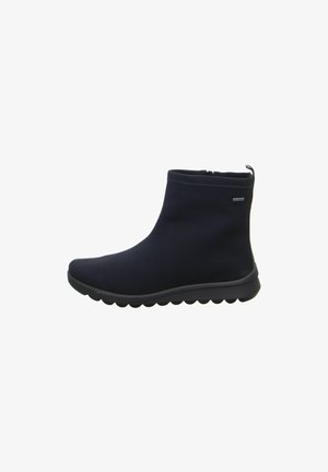 Bota negra de tobillo con parte superior de tela lisa, puntera redondeada, cremallera lateral, lengüeta en el talón y suela de goma texturizada con patrón de ondas.