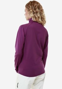 Maglietta a maniche lunghe viola con colletto alto, realizzata in tessuto morbido. Presenta maniche raglan e una vestibilità affusolata.
