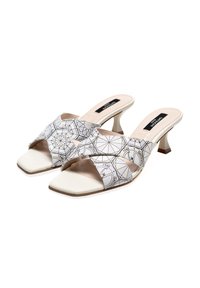 Mule con tacco aperto e punta con un motivo geometrico bianco e nero su fasce di tessuto, caratterizzate da una comoda soletta beige e un tacco sottile.