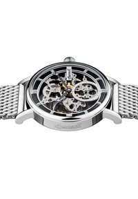 Orologio meccanico argento con quadrante trasparente, che mostra ingranaggi intricati e un quadrante nero. Presenta un bracciale in maglia argentata e dettagli dorati.