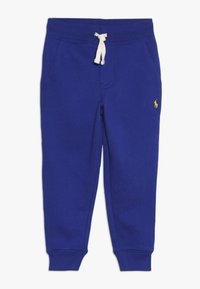 Pantalones de chándal azules hechos de un material suave, con una cintura elástica y un cordón blanco, bolsillos laterales y un pequeño detalle de logo amarillo.