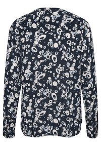 Mörkblå långärmad skjorta med ett blandat mönster av vita och ljusblå cirklar och ovaler, tillverkad av ett texturerat tyg.