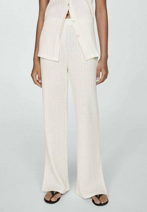 Leichte, elfenbeinfarbene Strickhosen mit weitem Bein, die ein strukturiertes Muster aufweisen und mit einem passenden, cropped Button-Up-Oberteil kombiniert sind.