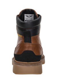 Brown leather boot with black accents, padded collar, textured panels, and rubber sole. Features a pull tab and branded label inside.