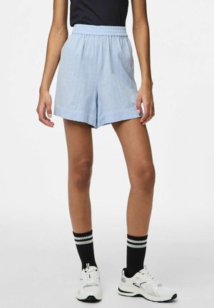 Lyseblå shorts med elastisk talje, prydet med lodrette striber og en løs, afslappet pasform. Kombineret med sort og hvidstribede sokker og sneakers.