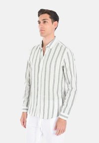 Camicia a maniche lunghe con righe verticali verdi e bianche, realizzata in tessuto leggero. Presenta un colletto button-down e polsini con dettagli a contrasto.