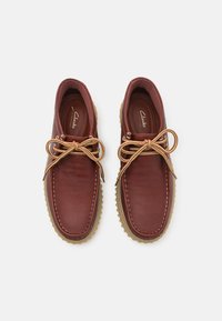 Brown leather shoes with a rounded toe, contrasting stitching, and gold-toned laces. Rubber sole for traction and durability.