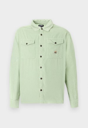 Hellgrünes Cordhemd mit langen Ärmeln, braunen Knöpfen und zwei verschließbaren Brusttaschen, eine mit einem kleinen Logoaufnäher.