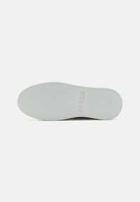 Bílá podrážka boty s jemnými horizontálními drážkami a slovem "FURLA" vyraženým poblíž paty na jednoduchém pozadí.