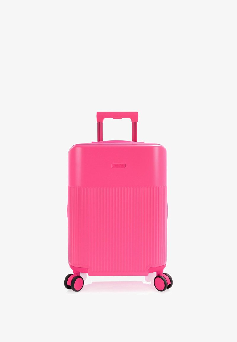 Valise rigide rose vif avec poignée télescopique et quatre roues doubles pivotantes, debout sur fond blanc.