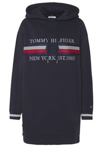 Marinblå huvtröja med grå, vit och röd randig detalj, med texten "TOMMY HILFIGER" och ankarlogo. Ribbad mudd och fåll.