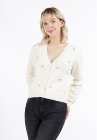 Světle krémový cardigan s výstřihem do V, zdobený kovovými zlatými srdíčky, se třemi knoflíky vpředu a žebrovanými manžetami.