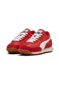Röda sneakers gjorda av mocka och syntetmaterial. Har vita detaljer, en vadderad krage och en strukturerad gummisula.