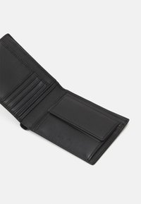 Portafoglio in pelle nera aperto per mostrare più scomparti per carte, una tasca piatta e una texture liscia con design minimalista.