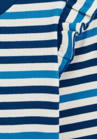 Blau- und weiß gestreifter Pulloverstoff mit gerippter Textur, der verschiedene Blautöne auf einem cremefarbenen Hintergrund zeigt.