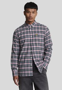 Camicia a maniche lunghe a quadri in blu navy scuro, rosso e bianco. Presenta un colletto button-down e un logo ricamato sul petto. Tessuto in cotone.