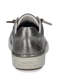 Metallinen hopea nahkalenkkari, jossa on pehmustettu sisustus, valkoinen pohja ja koristeelliset yksityiskohdat, kuten lenkkitappi takana.