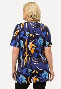 Kurzärmlige Tunika in Marineblau mit einem lebhaften Blumenmuster in Blau-, Gelb- und Orangetönen; lockere Passform, weicher Stoff, mittellang.