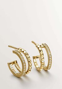 Pendientes de aro de oro con un diseño texturizado y tachonado, y una fila de rhinestones transparentes a lo largo del borde exterior. Forma circular, acabado suave.